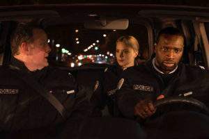 Trois policiers dans une voiture (joués par Grégory Gadebois, Virginie Efira et Omar Sy), dont on épie les regards les uns sur les autres.